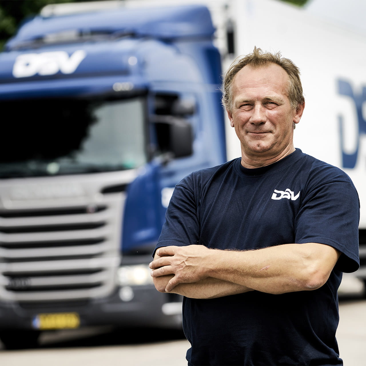 Mies seissoo sinisen DSV:n rekan edessä kädet ristissä ja hymyilee.